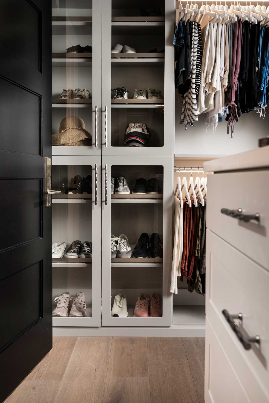 Custom closet design built-in featuring shoe racks in glass cabinets