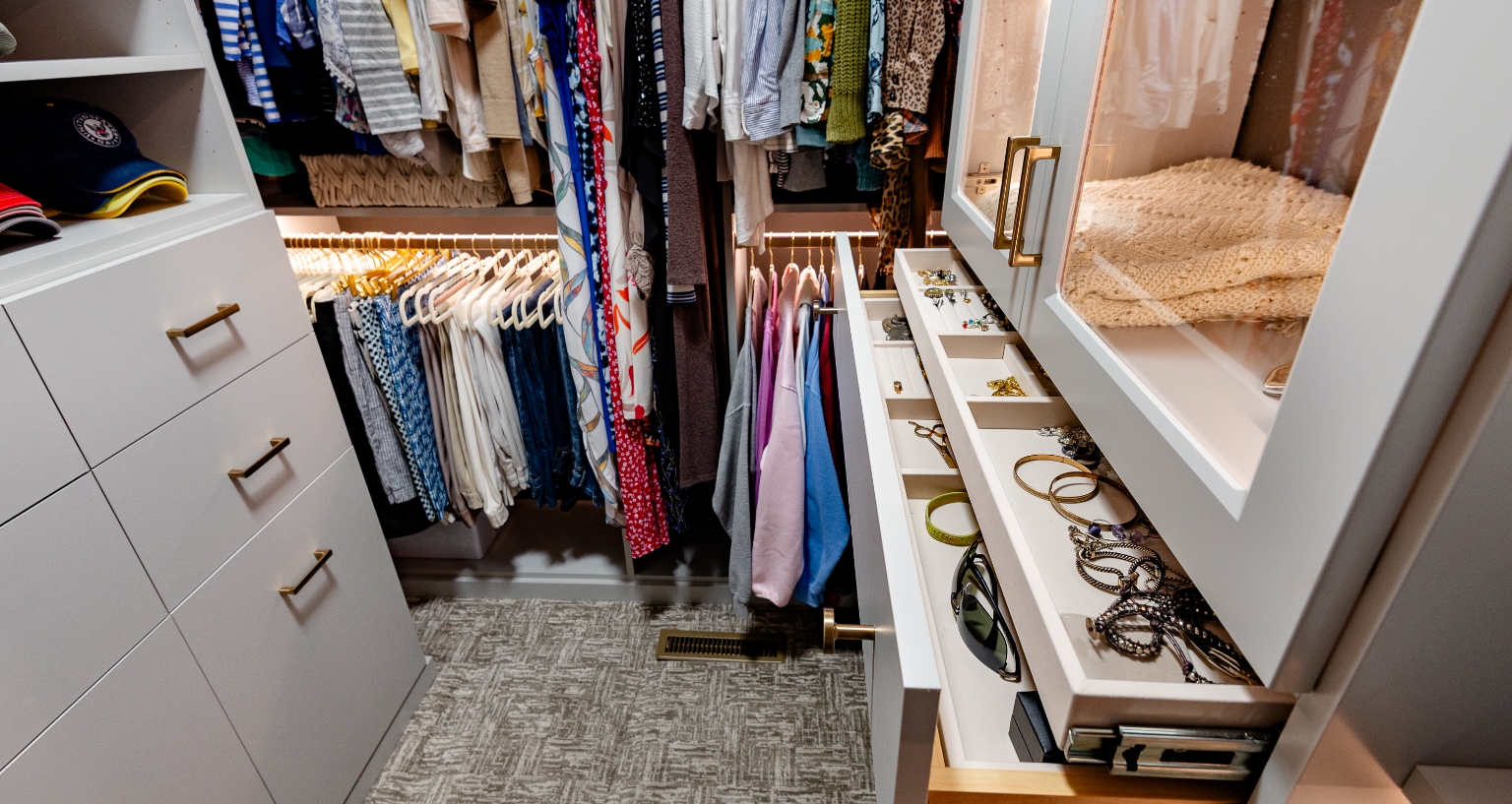 Smaller walk-in closet with organized beauty featuring jewelry drawers