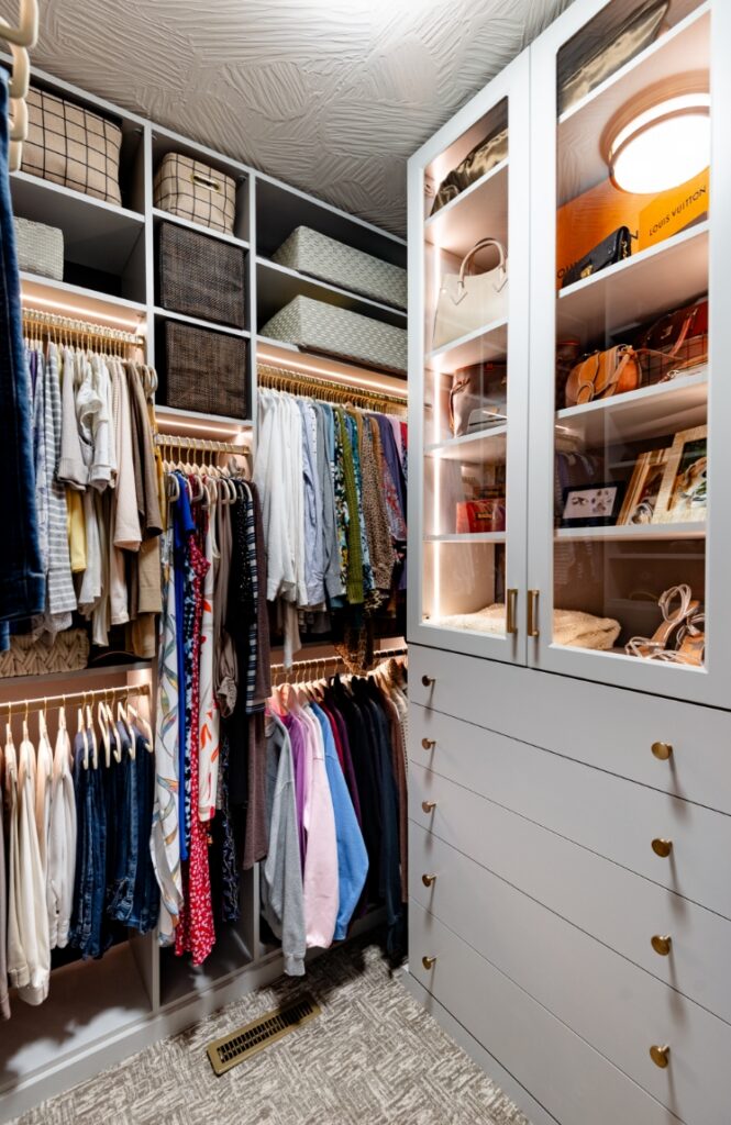 Smaller walk-in closet with organized beauty featuring dresser and cabinet built-ins.