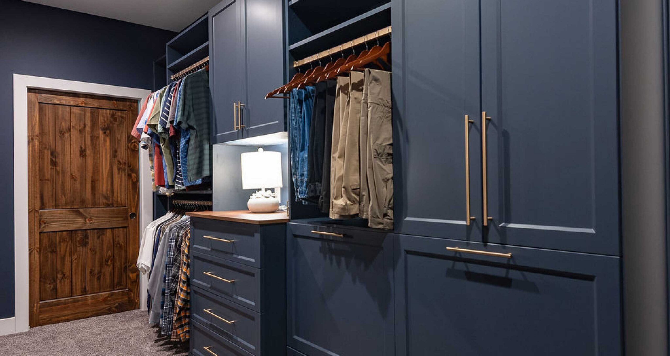 Slate blue closet cabinetry and dressers with hanging systems featured