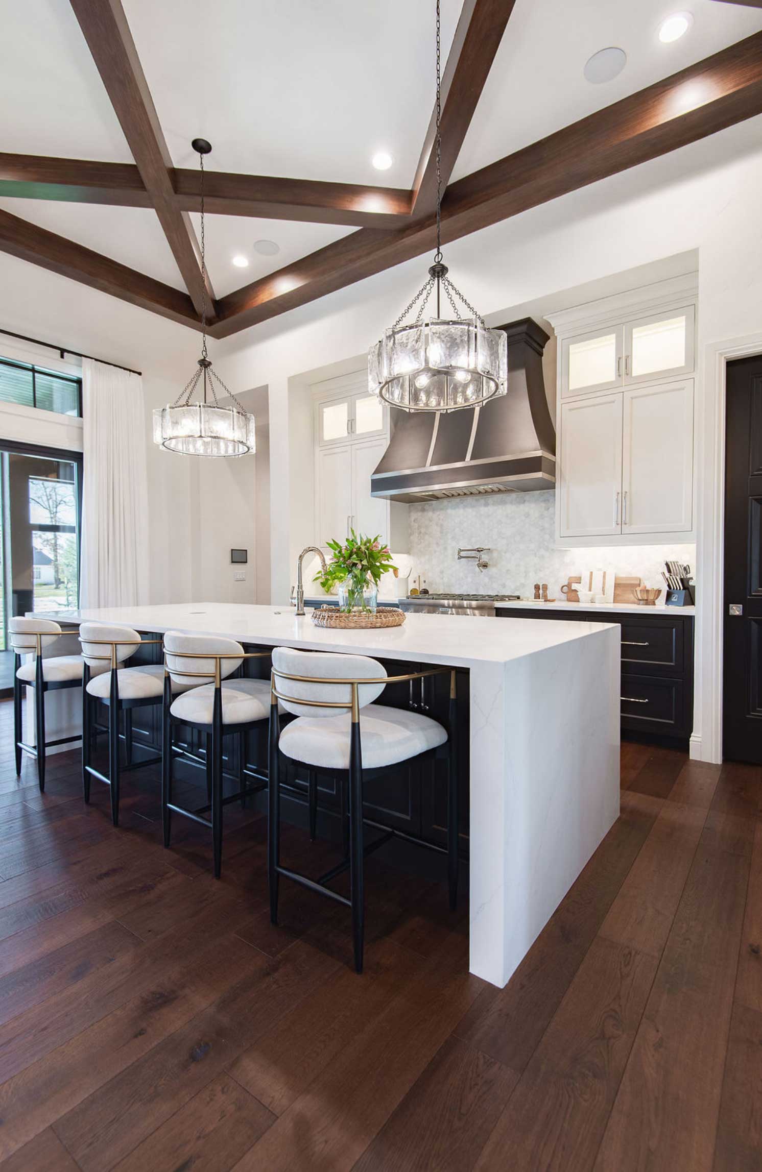 Elegant and open kitchen with white cabinetry with waterfall bar and high ceilings